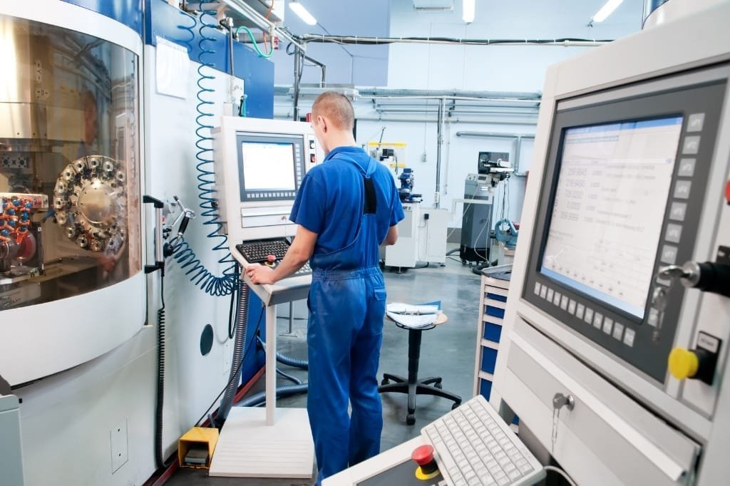 CNC operator at machine control panel